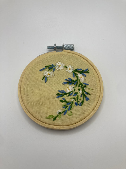 Embroidery hoop with floral design on a plain background